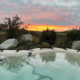 Bio.design-Pool in geschwungener Form mit Abendstimmung und Sonnenuntergang