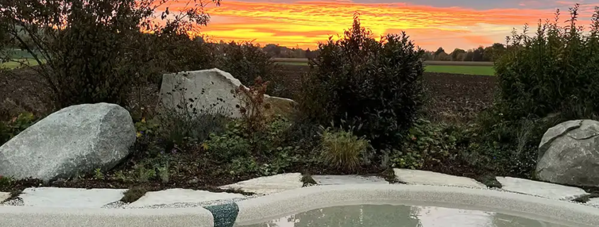 Bio.design-Pool in geschwungener Form mit Abendstimmung und Sonnenuntergang
