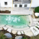 Bio.design-Pool in geschwungener Form vor Terrasse mit Randbepflanzung und Gartendusche