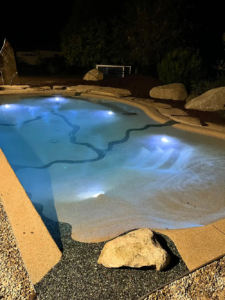 Bio.design-Pool in stimmungsvoller Abendbeleuchtung mit Randbepflanzung