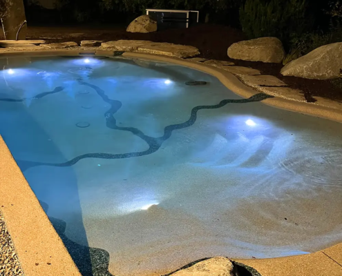 Bio.design-Pool in stimmungsvoller Abendbeleuchtung mit Randbepflanzung