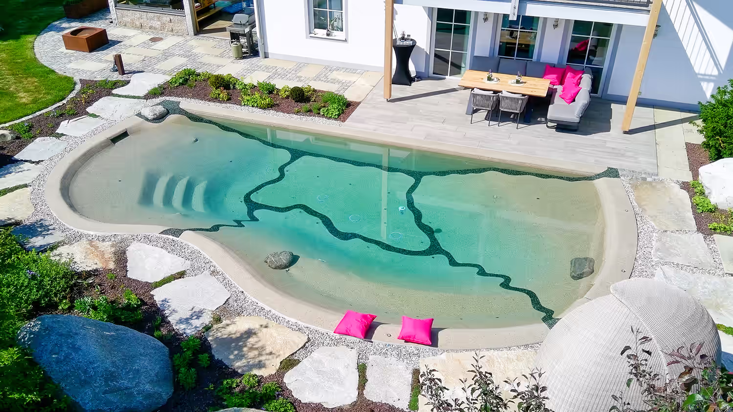Bio.design-Pool mit Blick auf die Terrasse – naturnaher Swimmingpool mit gestalteter Außenanlage